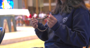 Closeup student holds rosary